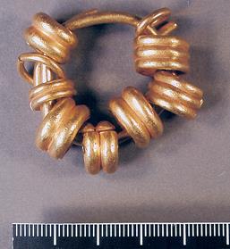 Photograph of a set of Bronze Age gold rings threaded onto one large gold ring found in Gresham.