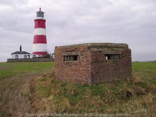 View of Happisburgh Lighthouse in the background and a World War Two pillbox in the foreground.